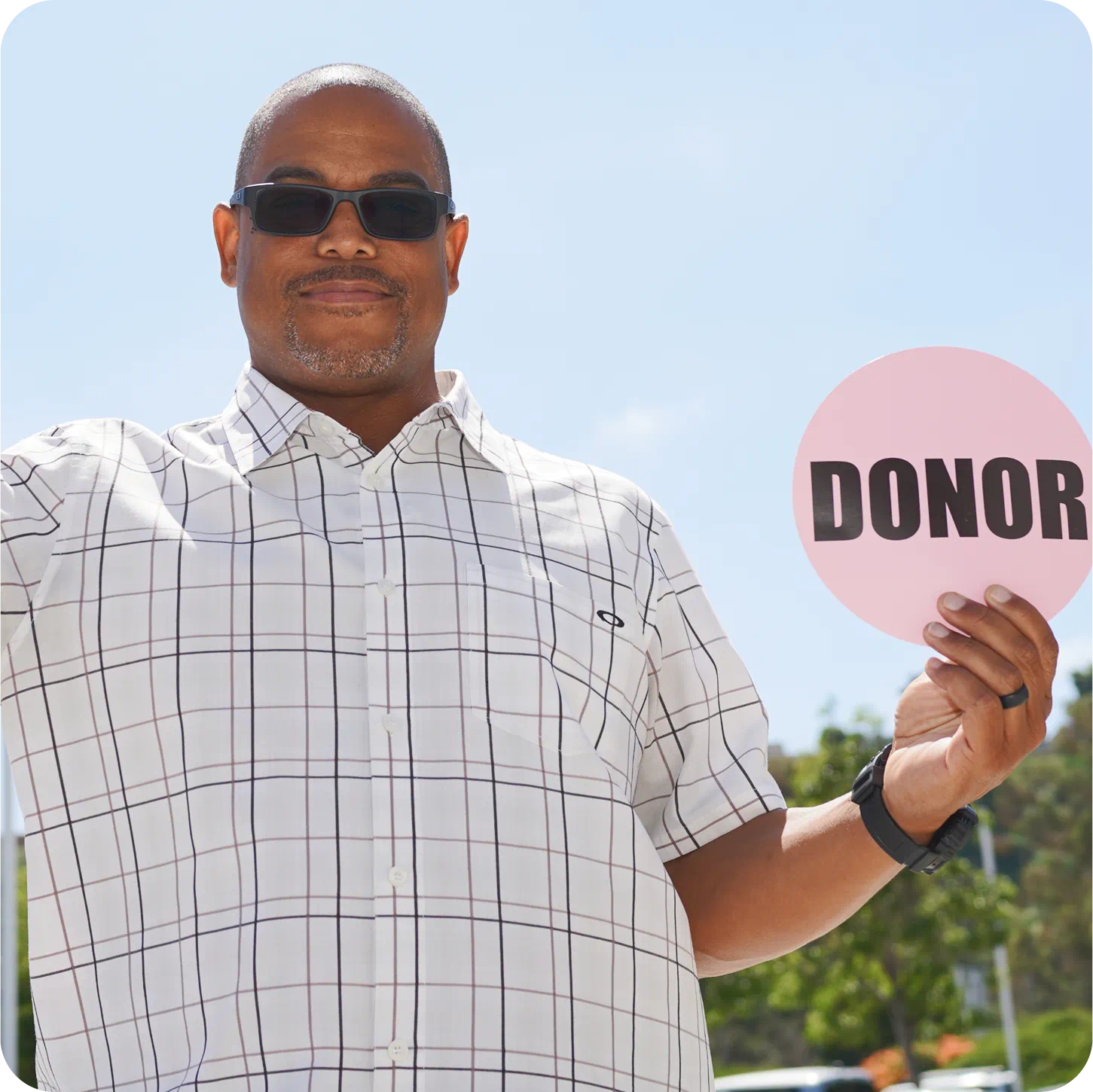 Portrait of a man holding a DONOR sign