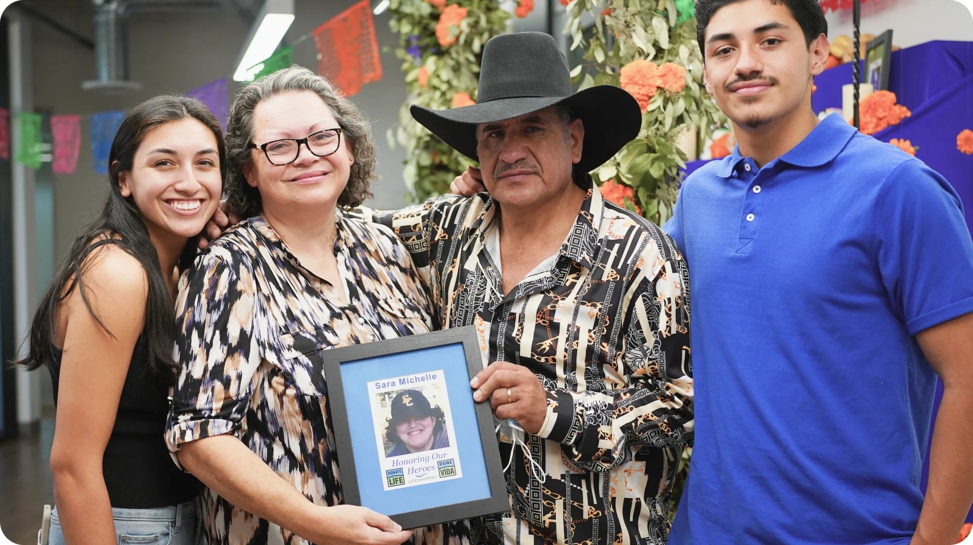 A family stands together holding a photo of a young woman