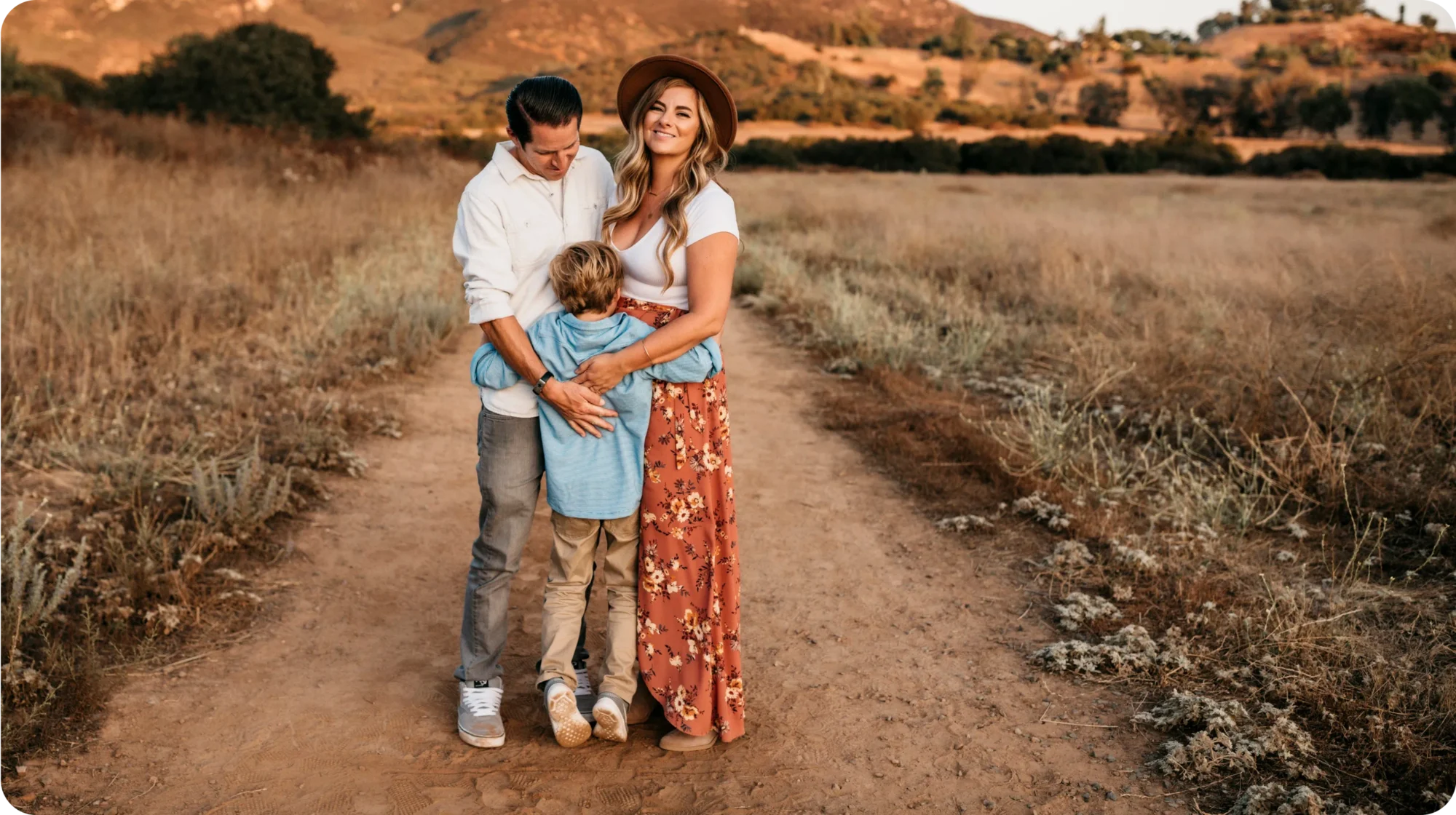 A portrait of Tawny, Chris and Gavin Raceles embracing in a scenic setting