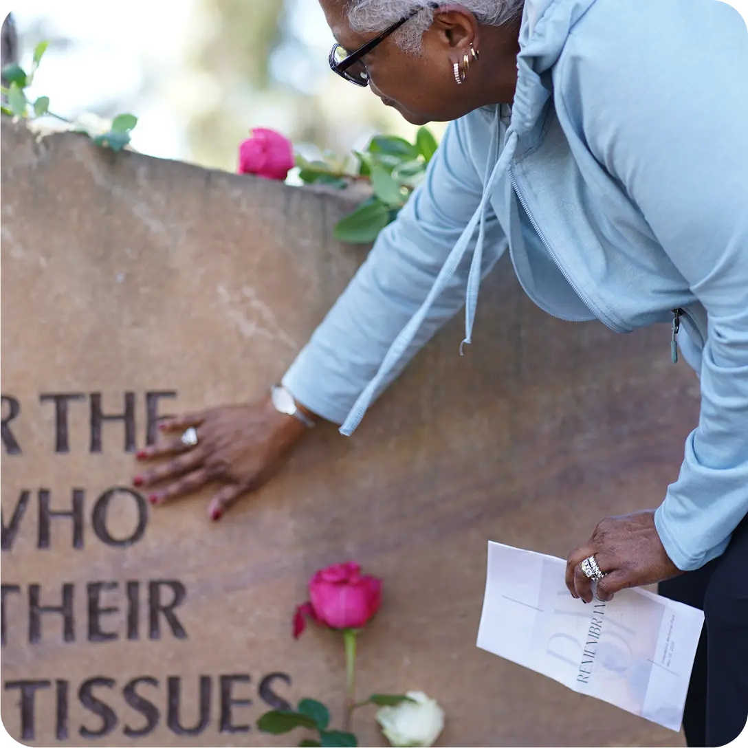 Woman pays respect at a memorial stone